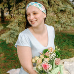Woman smiling while wearing the Hope Floral on Ivory headband, the perfect non-slip accessory for work or workouts.