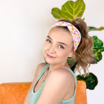 A woman wearing the hair accessory Don't Be Jelly headband with colorful jelly bean pattern, perfect for workouts, long shifts, and play days.