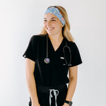 A nurse smiling with long hair while wearing the Born to Yap Forced to Chart headband for cute hairstyles and comfortable all-day wear.