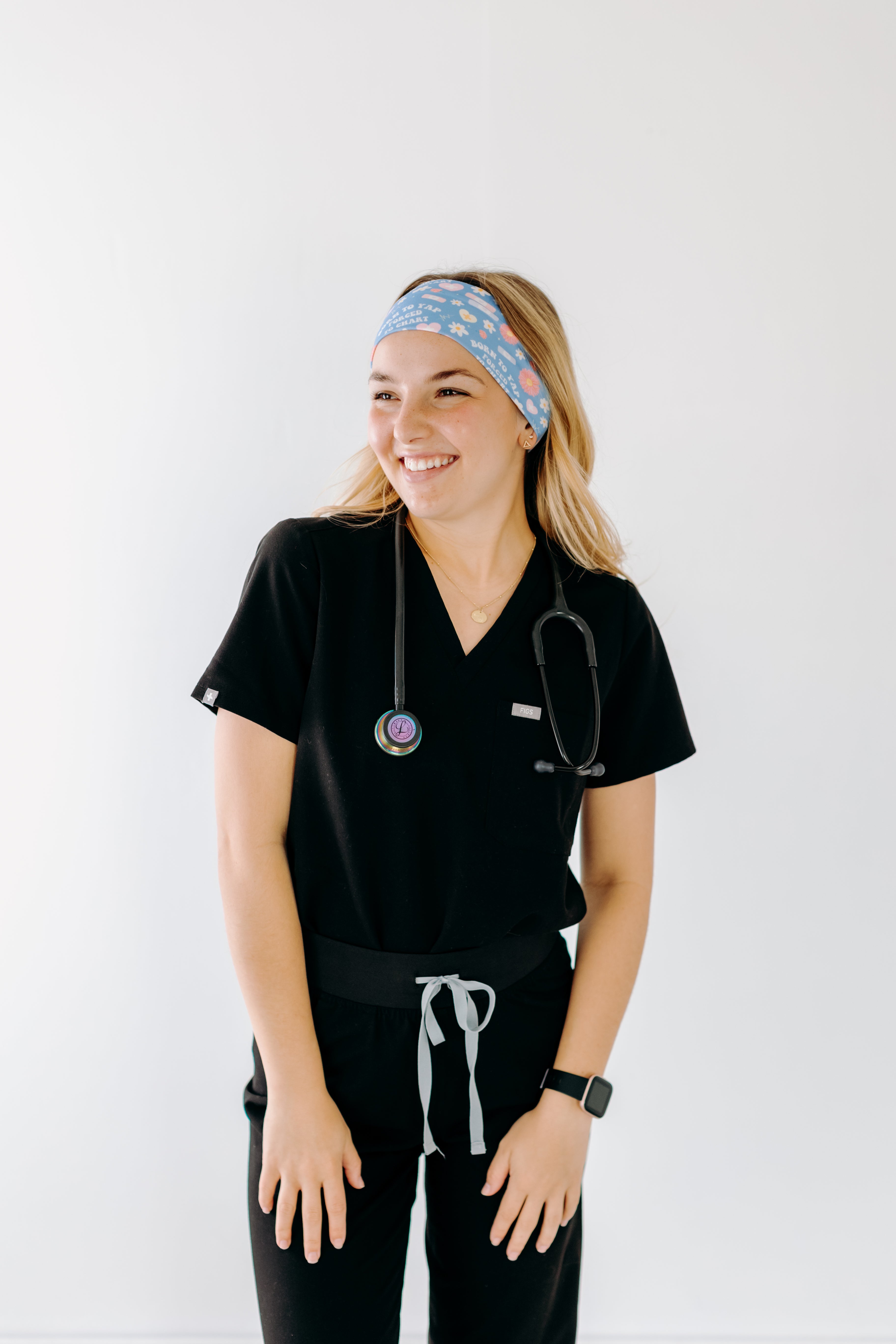 A nurse smiling with long hair while wearing the Born to Yap Forced to Chart headband for cute hairstyles and comfortable all-day wear.