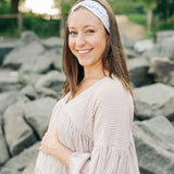 Woman smiling, wearing a Fortitude headband, showcasing its functional, versatile design. The headband is non-slip, sweat-absorbent, and perfect for workouts or daily wear.