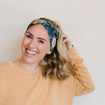 Adult women's black headband with hand-drawn gold, teal and coral roses with green stems and leaves