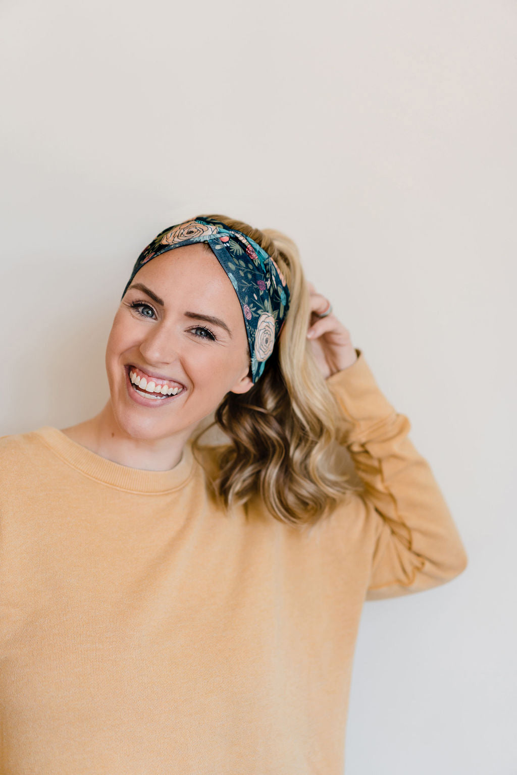 Adult women's black headband with hand-drawn gold, teal and coral roses with green stems and leaves