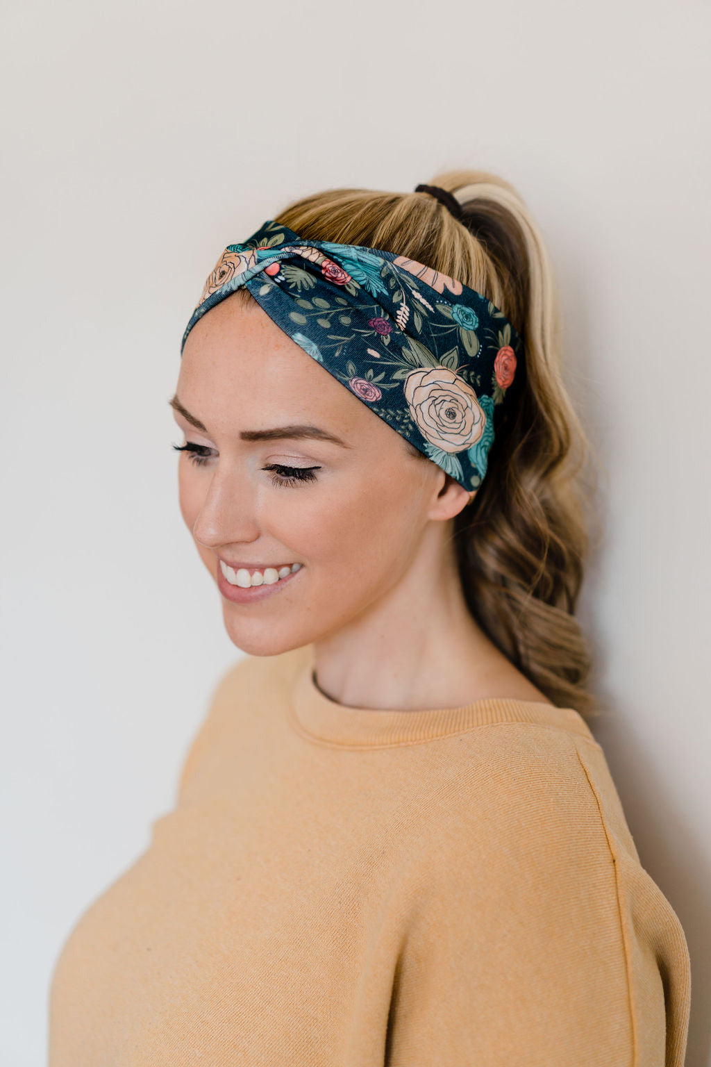 Adult women's black headband with hand-drawn gold, teal and coral roses with green stems and leaves