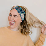 Adult women's black headband with hand-drawn gold, teal and coral roses with green stems and leaves