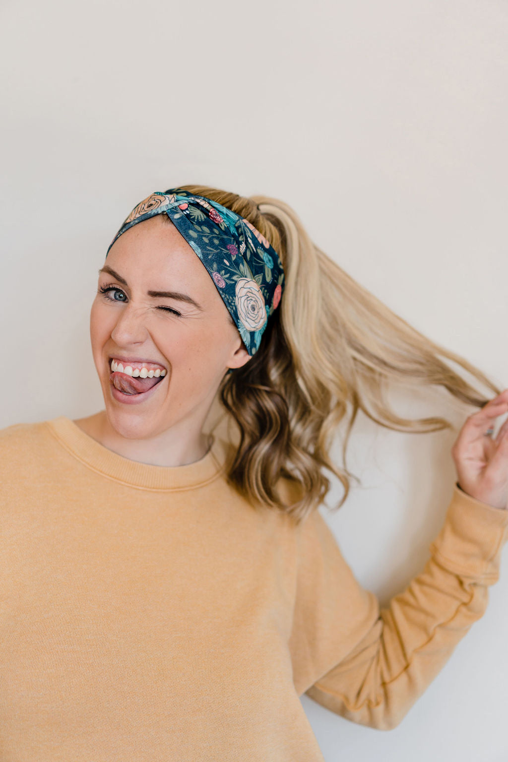 Adult women's black headband with hand-drawn gold, teal and coral roses with green stems and leaves