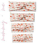 A group of white twist knot headbands for you and your mini me, featuring a pink and red butterfly and flower design, with adjustable fit for toddlers and babies.