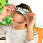 A woman wearing a Pinch Proof Lilac Market Headband, showcasing its functional and stylish design for confident wear during various activities.