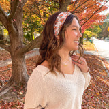 Woman smiling outdoors wearing It's Giving Thanks headband, showcasing its versatile 3-in-1 twist style and non-slip design against a tree backdrop.