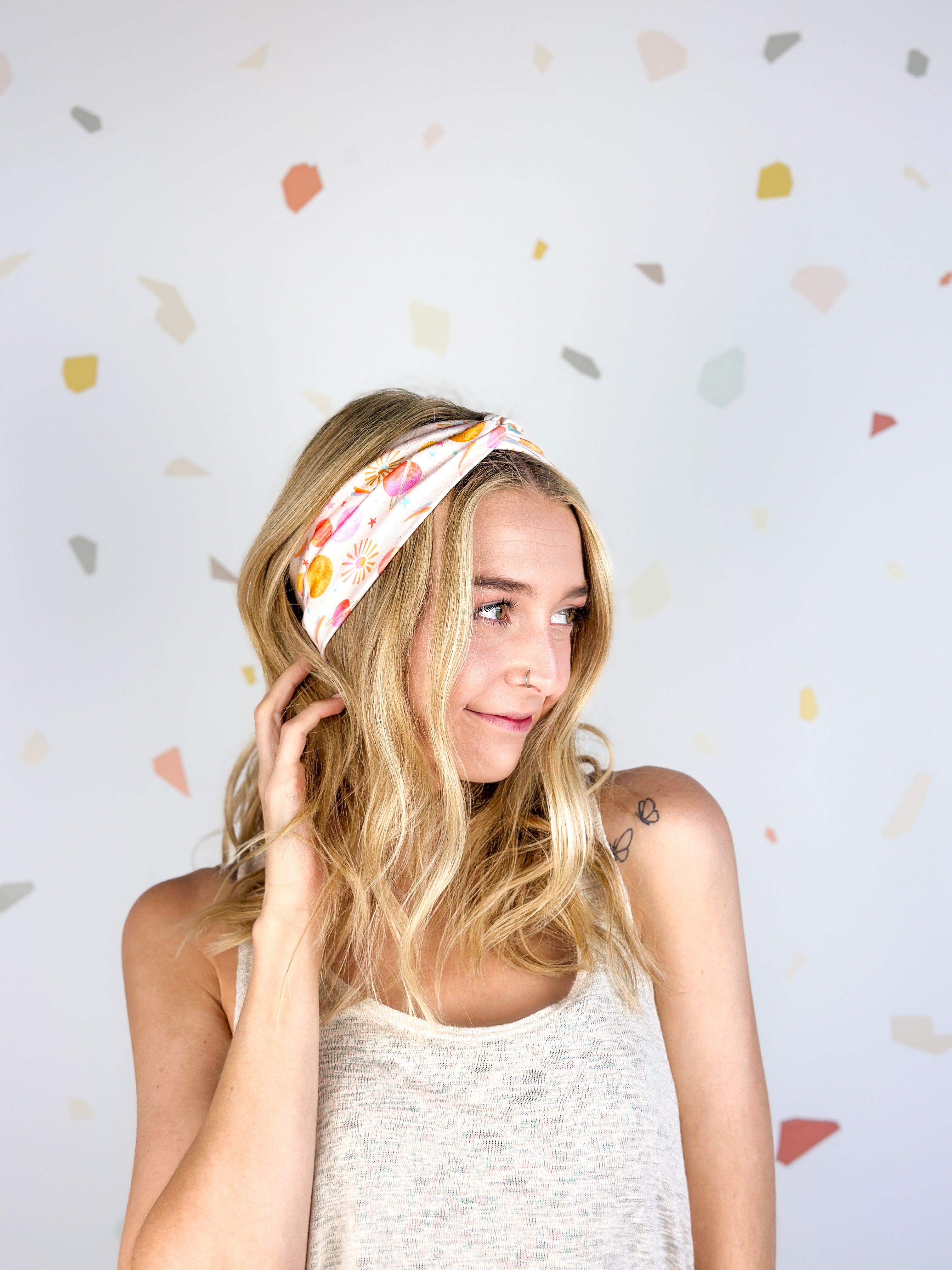 Woman smiling, wearing Field Trip to the Stars headband; ultra-stretchy, versatile, double-layered, non-slip, and sweat-absorbent. Ideal for workouts, long shifts, or playdays.