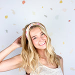 Woman smiling, wearing Field Trip to the Stars headband; ultra-stretchy, versatile, double-layered, non-slip, and sweat-absorbent. Ideal for workouts, long shifts, or playdays.