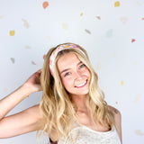 Woman smiling, wearing Field Trip to the Stars headband; ultra-stretchy, versatile, double-layered, non-slip, and sweat-absorbent. Ideal for workouts, long shifts, or playdays.