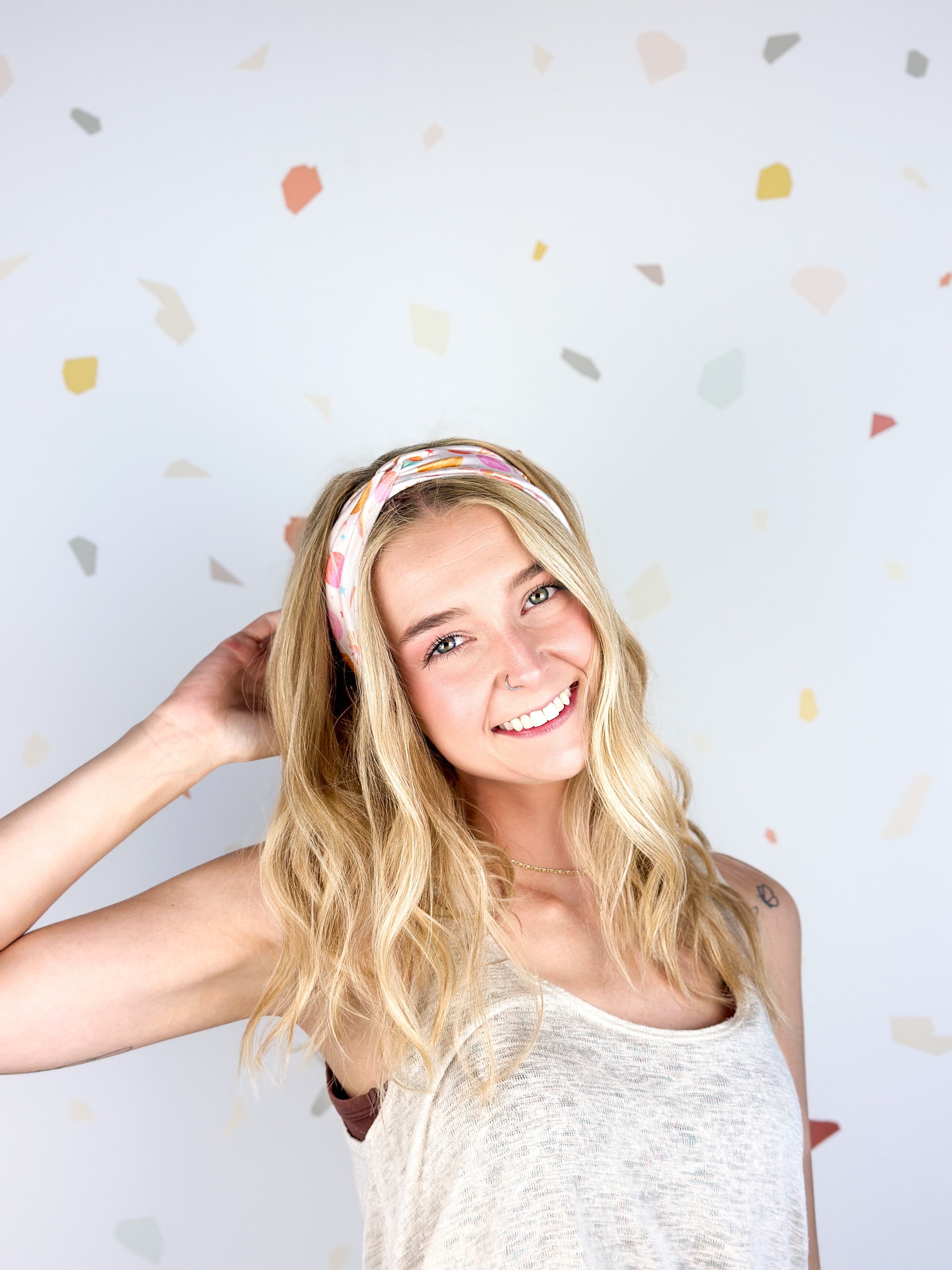 Woman smiling, wearing Field Trip to the Stars headband; ultra-stretchy, versatile, double-layered, non-slip, and sweat-absorbent. Ideal for workouts, long shifts, or playdays.