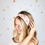 Woman smiling, wearing Field Trip to the Stars headband; ultra-stretchy, versatile, double-layered, non-slip, and sweat-absorbent. Ideal for workouts, long shifts, or playdays.