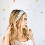 Woman smiling, wearing the Avonlea headband. The headband is a versatile, ultra-stretchy poly-knit blend, providing multiple ways to wear for various activities.