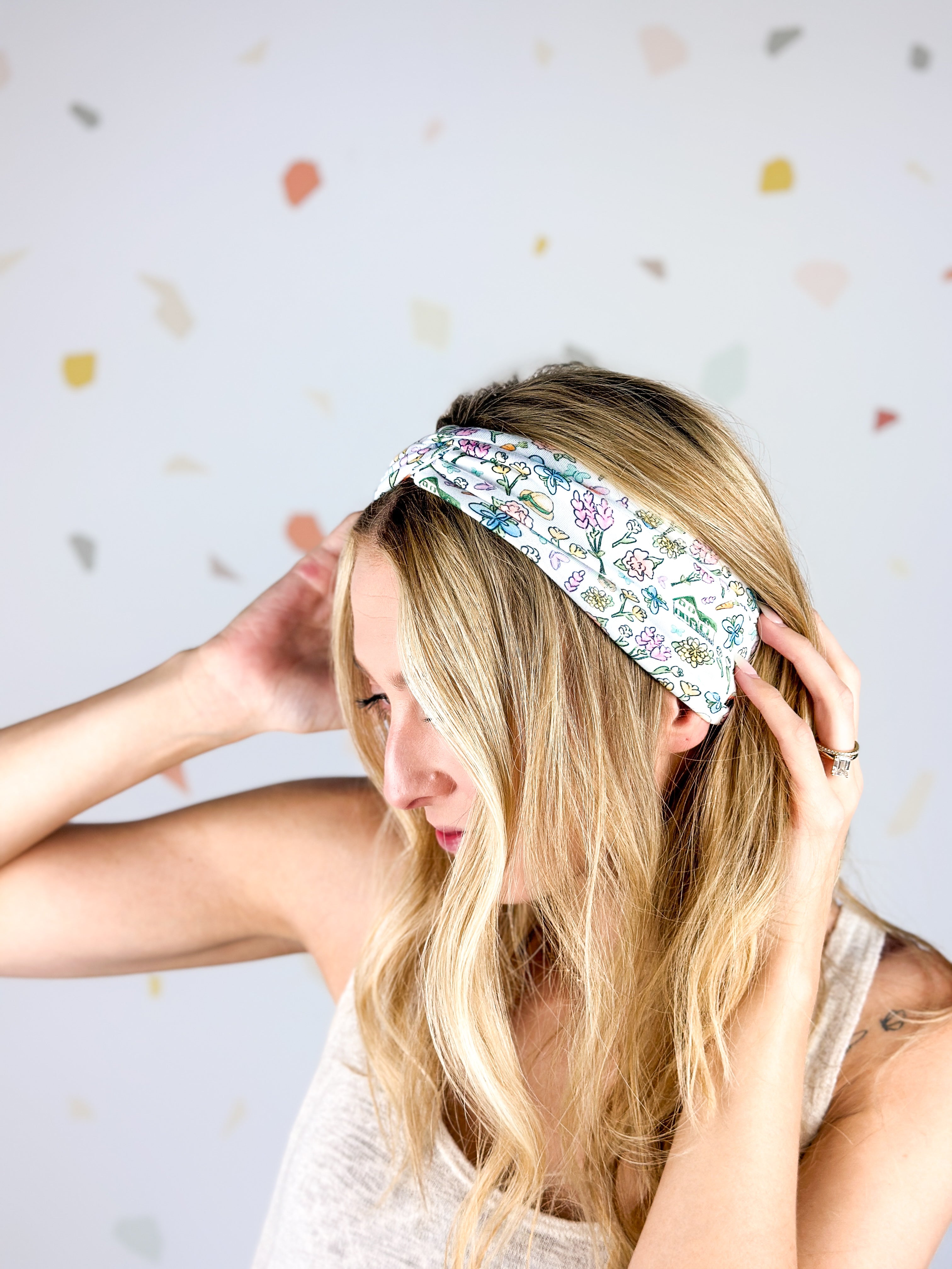 Woman smiling, wearing the Avonlea headband. The headband is a versatile, ultra-stretchy poly-knit blend, providing multiple ways to wear for various activities.