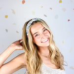 Woman smiling, wearing the Avonlea headband. The headband is a versatile, ultra-stretchy poly-knit blend, providing multiple ways to wear for various activities.