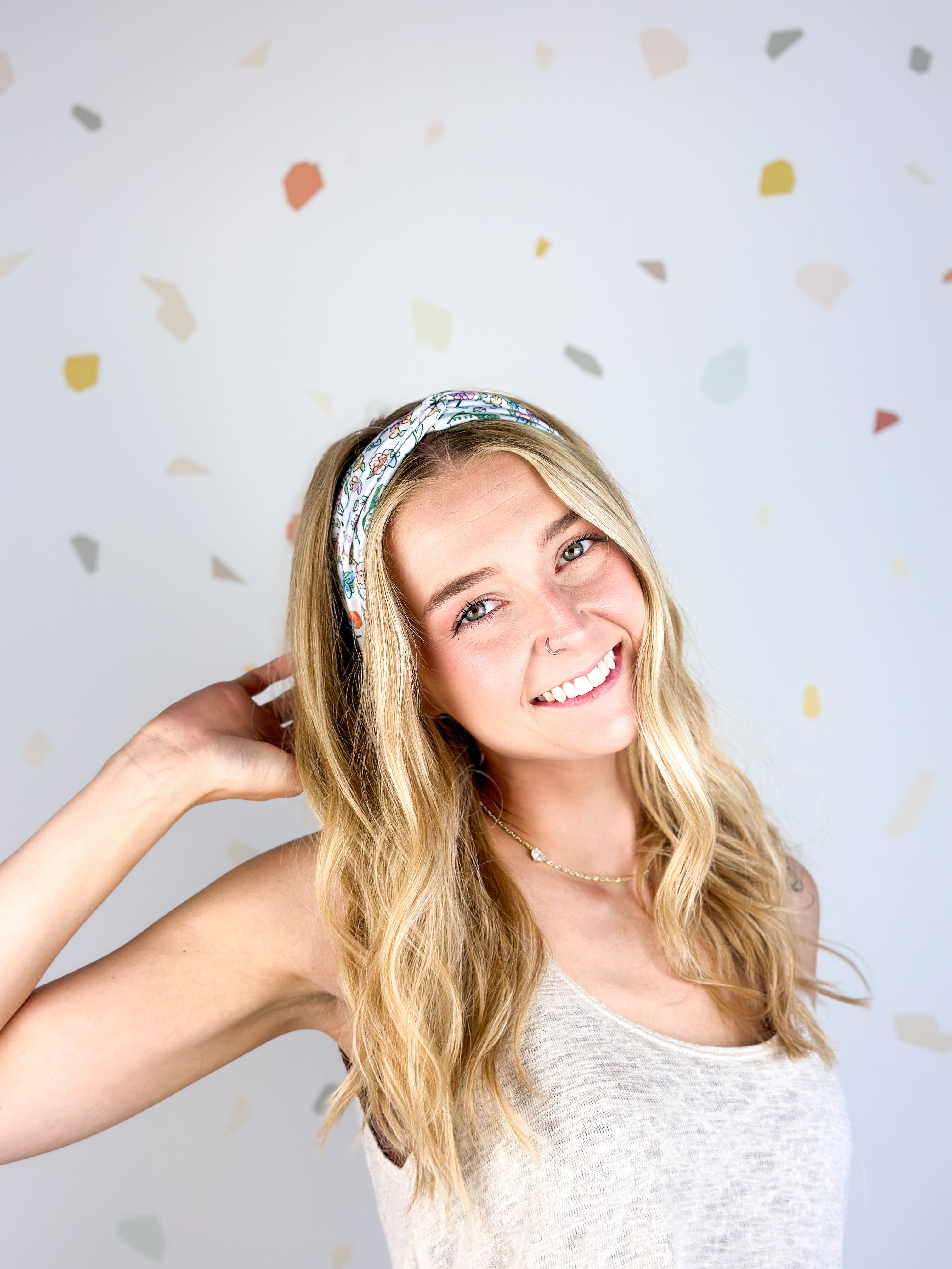 Woman smiling, wearing the Avonlea headband. The headband is a versatile, ultra-stretchy poly-knit blend, providing multiple ways to wear for various activities.