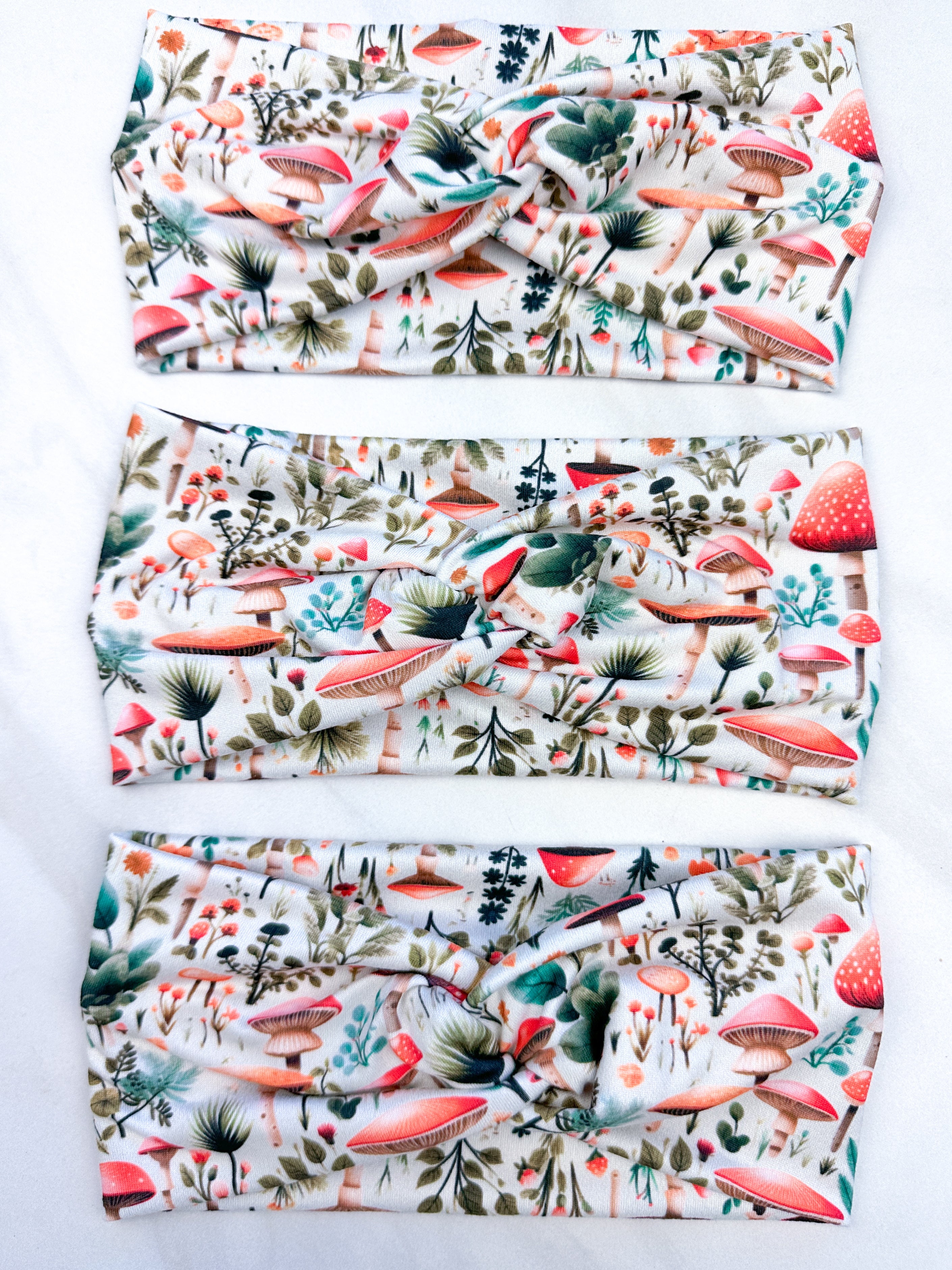 An Enchanted Garden headband with a mushroom and plant pattern, featuring a knot design. Versatile 3-in-1 twist style, sweat-absorbent, non-slip, and machine washable. Functional and stylish for any activity.