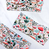 An Enchanted Garden headband with a mushroom and plant pattern, featuring a knot design. Versatile 3-in-1 twist style, sweat-absorbent, non-slip, and machine washable. Functional and stylish for any activity.