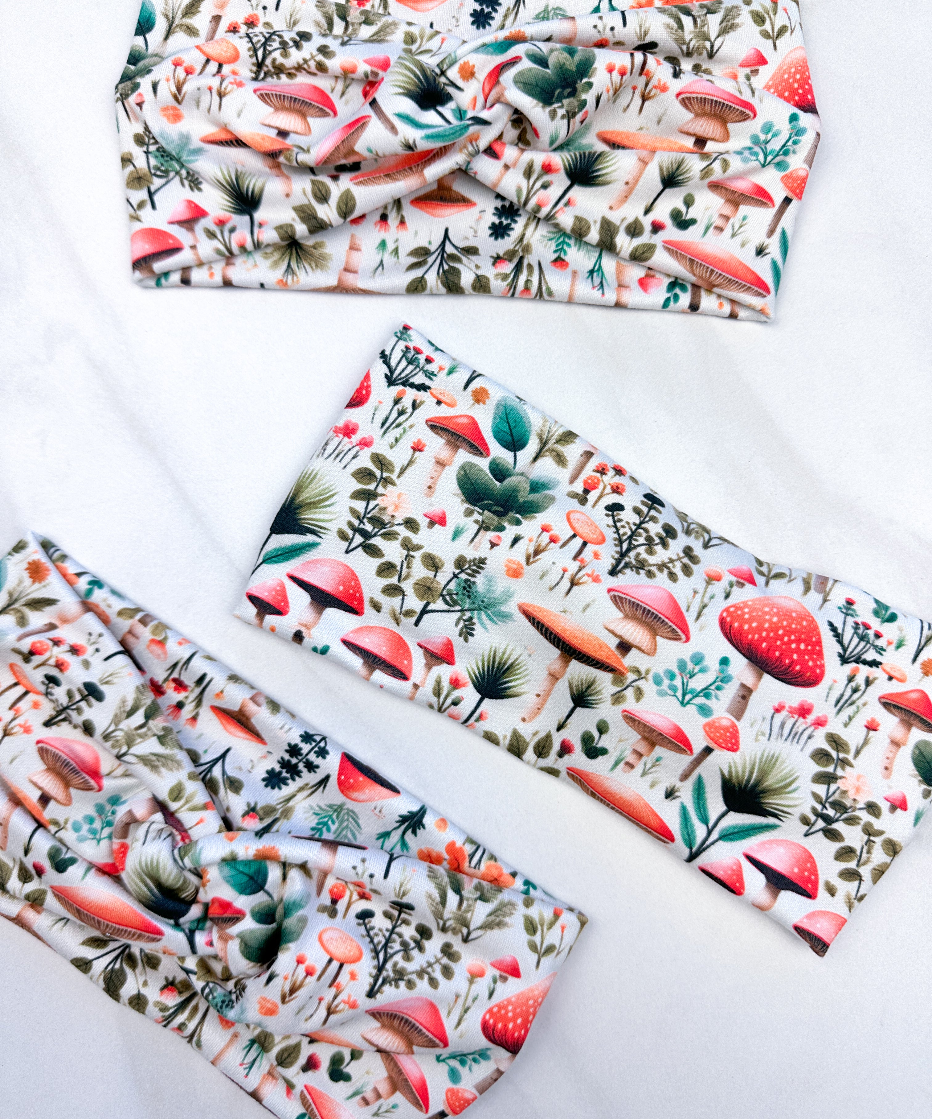 An Enchanted Garden headband with a mushroom and plant pattern, featuring a knot design. Versatile 3-in-1 twist style, sweat-absorbent, non-slip, and machine washable. Functional and stylish for any activity.