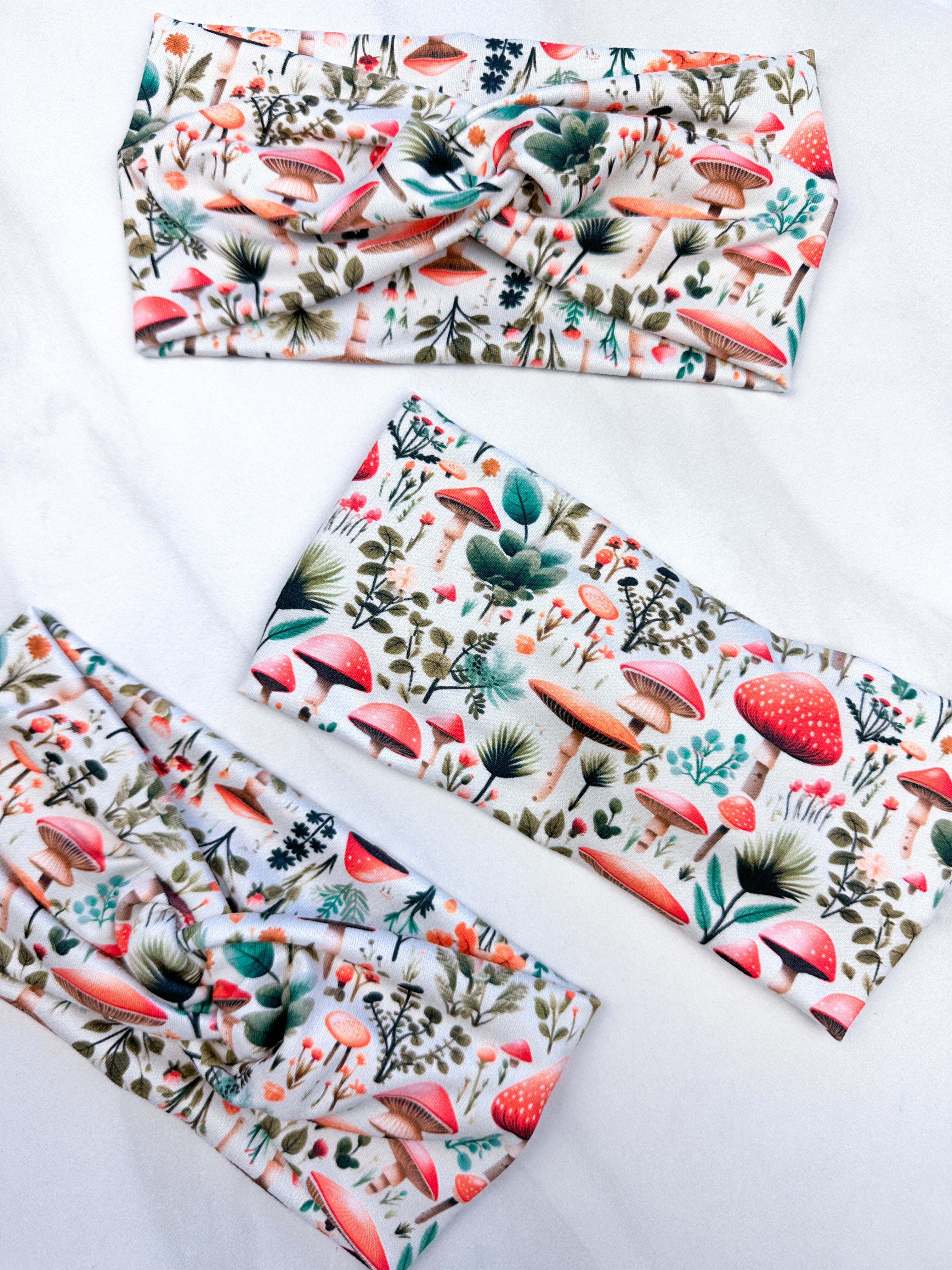 An Enchanted Garden headband with a mushroom and plant pattern, featuring a knot design. Versatile 3-in-1 twist style, sweat-absorbent, non-slip, and machine washable. Functional and stylish for any activity.