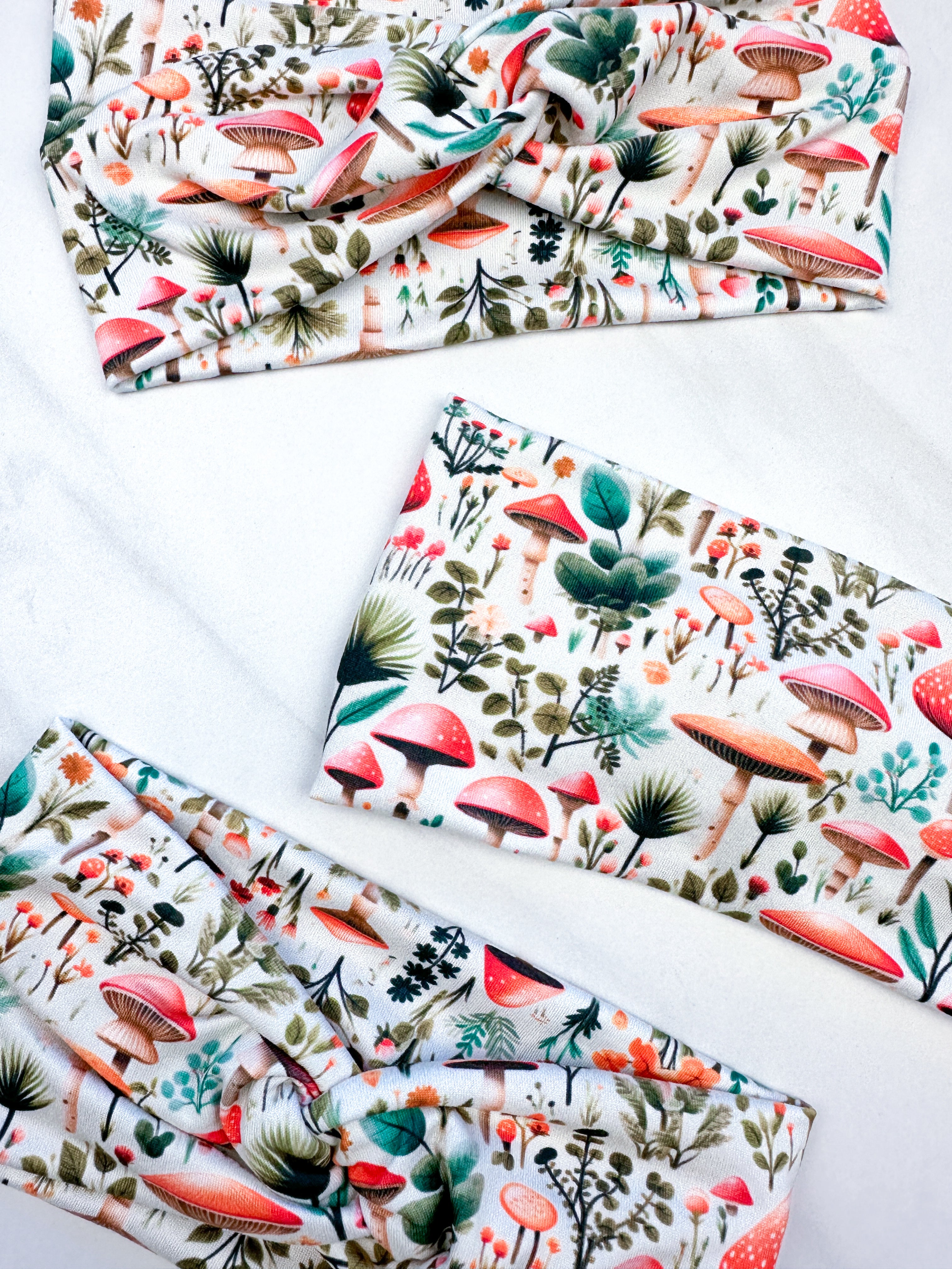 An Enchanted Garden headband with a mushroom and plant pattern, featuring a knot design. Versatile 3-in-1 twist style, sweat-absorbent, non-slip, and machine washable. Functional and stylish for any activity.