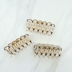A group of the Out Of Office Lilac clip. 3.6 inches long, shiny gold metal, perfect for all hair types. Hinge closure for a secure fit.