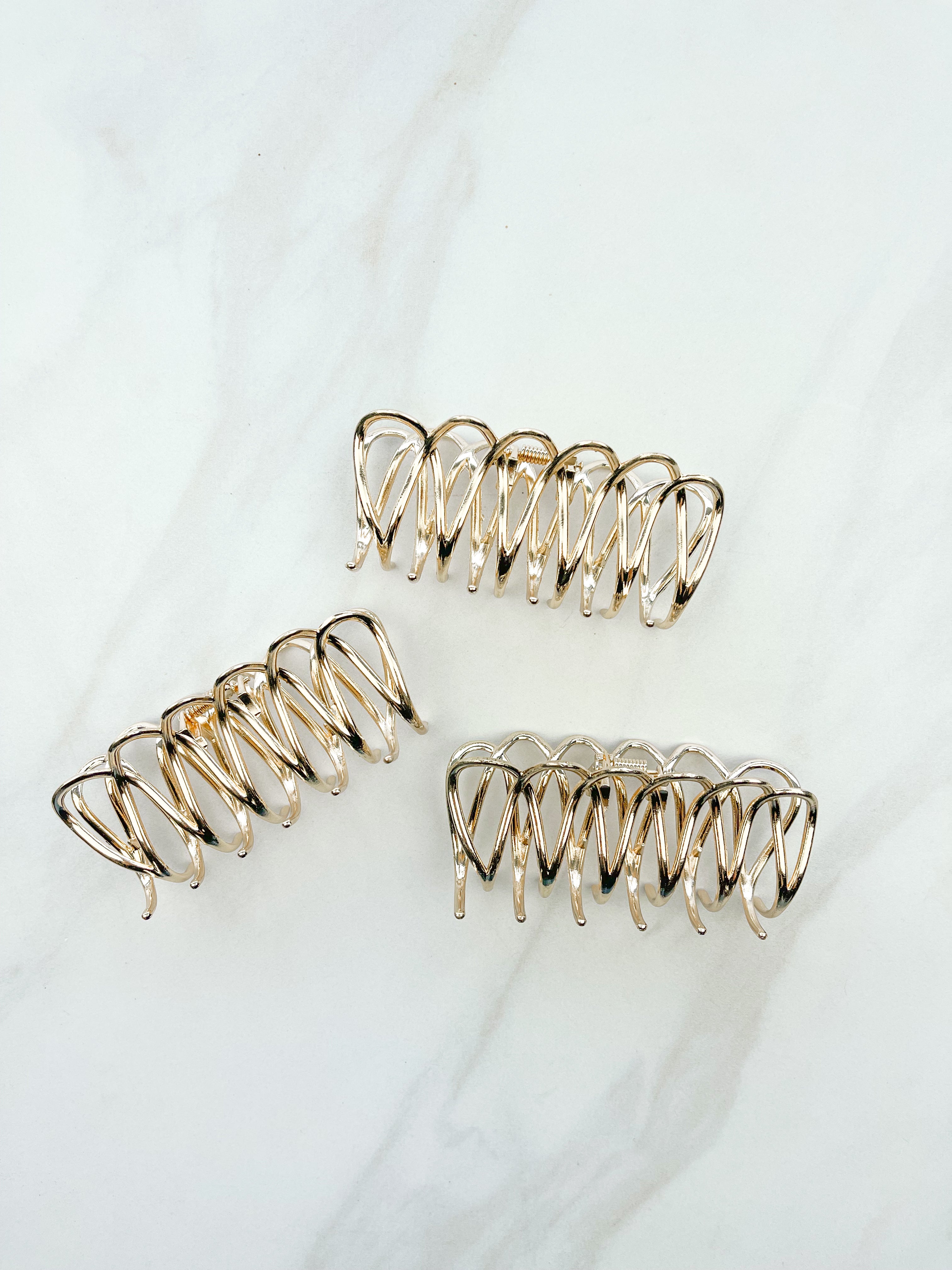 A group of the Out Of Office Lilac clip. 3.6 inches long, shiny gold metal, perfect for all hair types. Hinge closure for a secure fit.