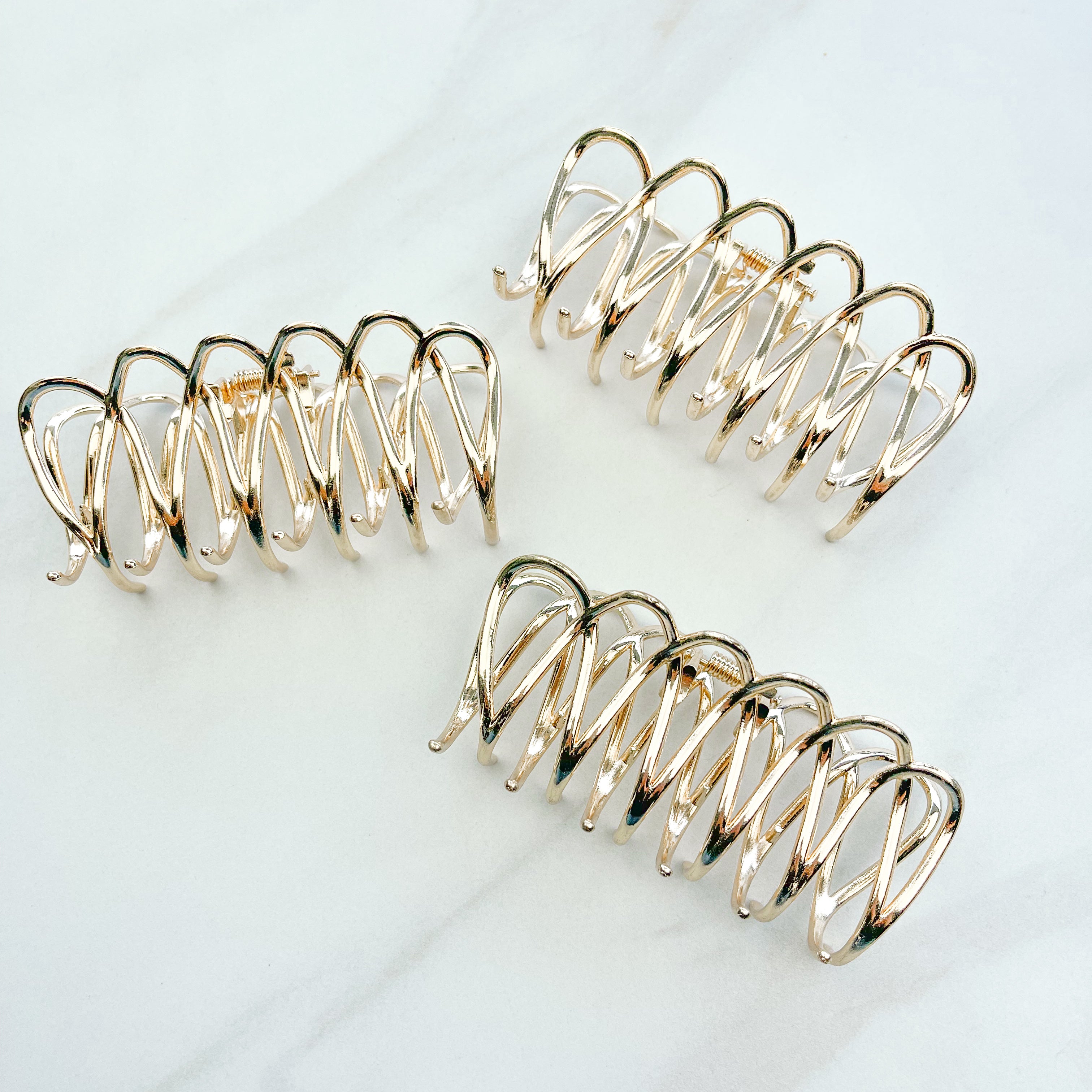 A group of the Out Of Office Lilac clip. 3.6 inches long, shiny gold metal, perfect for all hair types. Hinge closure for a secure fit.