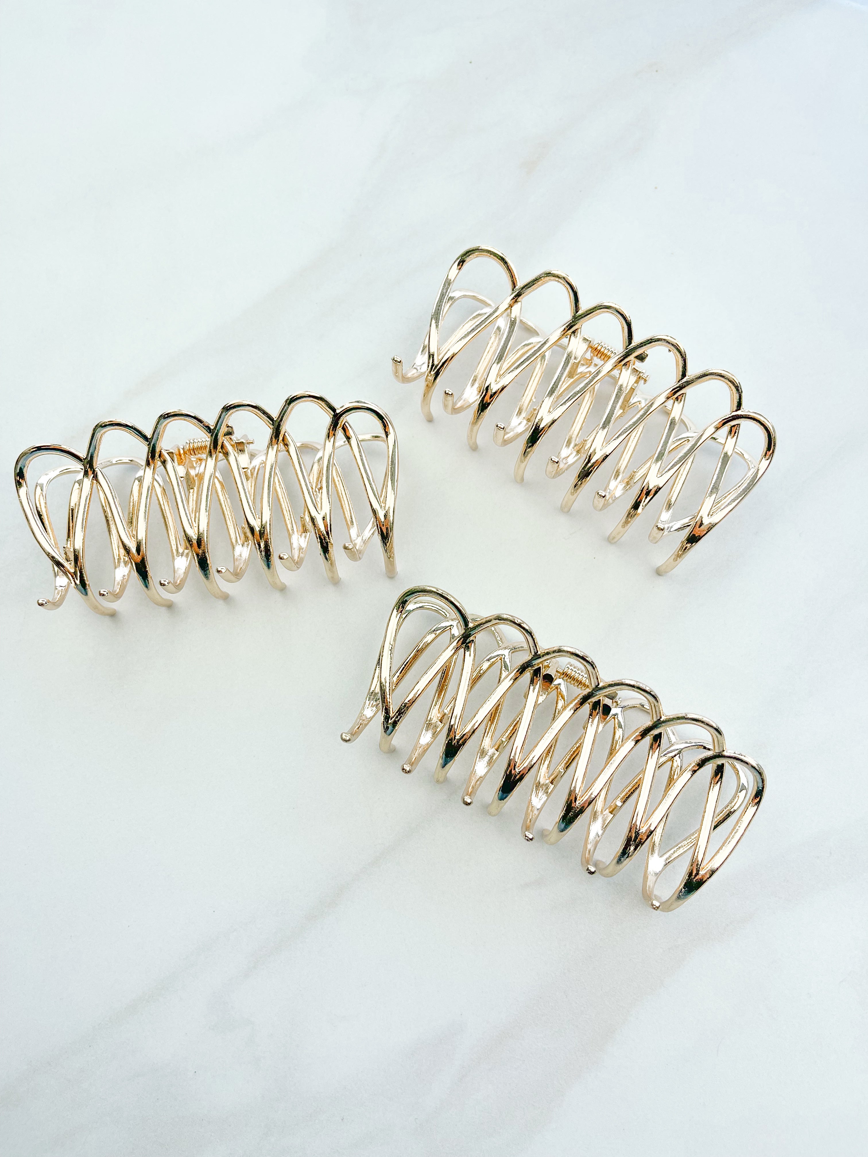 A group of the Out Of Office Lilac clip. 3.6 inches long, shiny gold metal, perfect for all hair types. Hinge closure for a secure fit.
