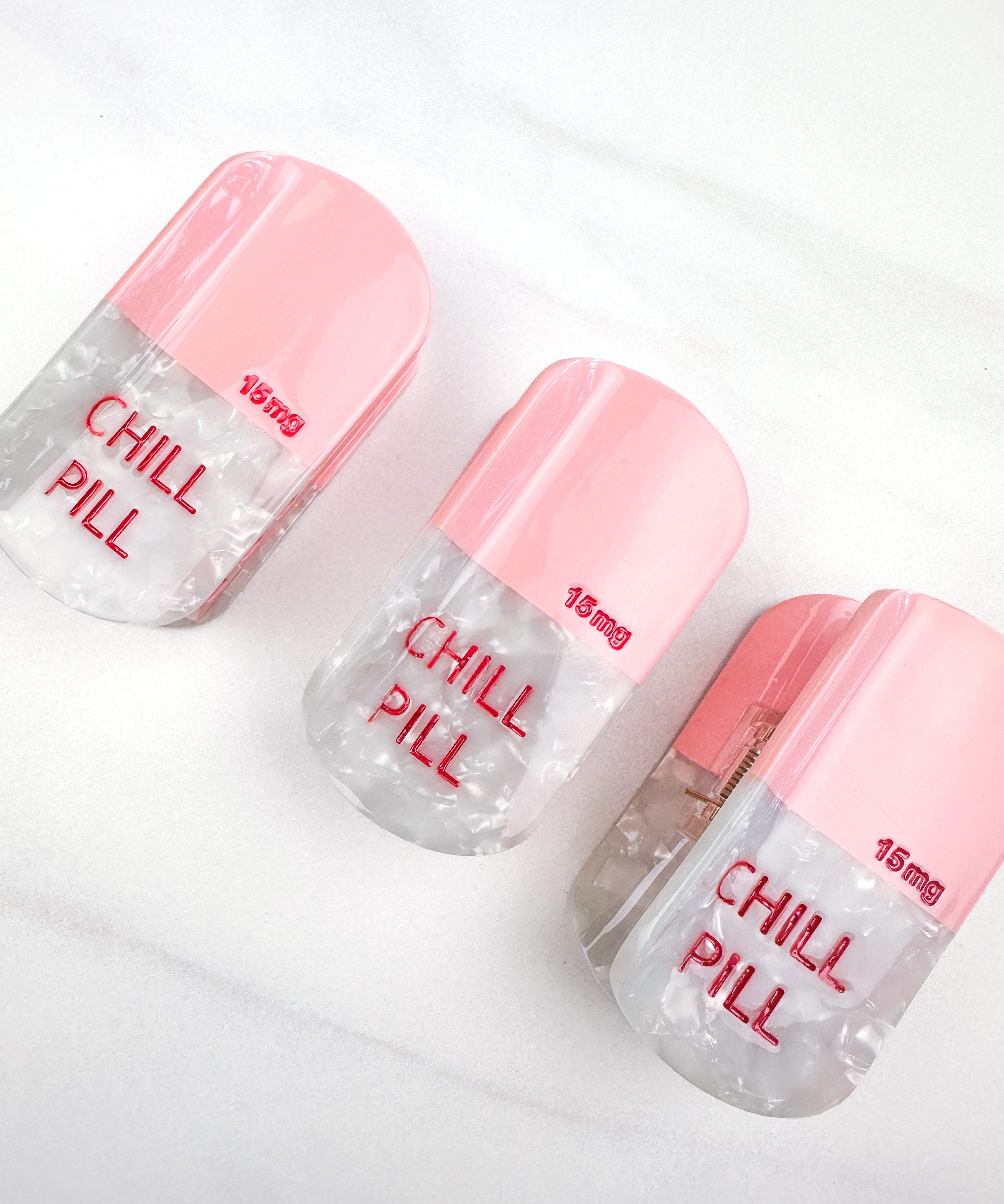 A group of hair claw clips that look like pink pills, featuring the Lilac Clip's glossy material and hinge closure for all hair types.