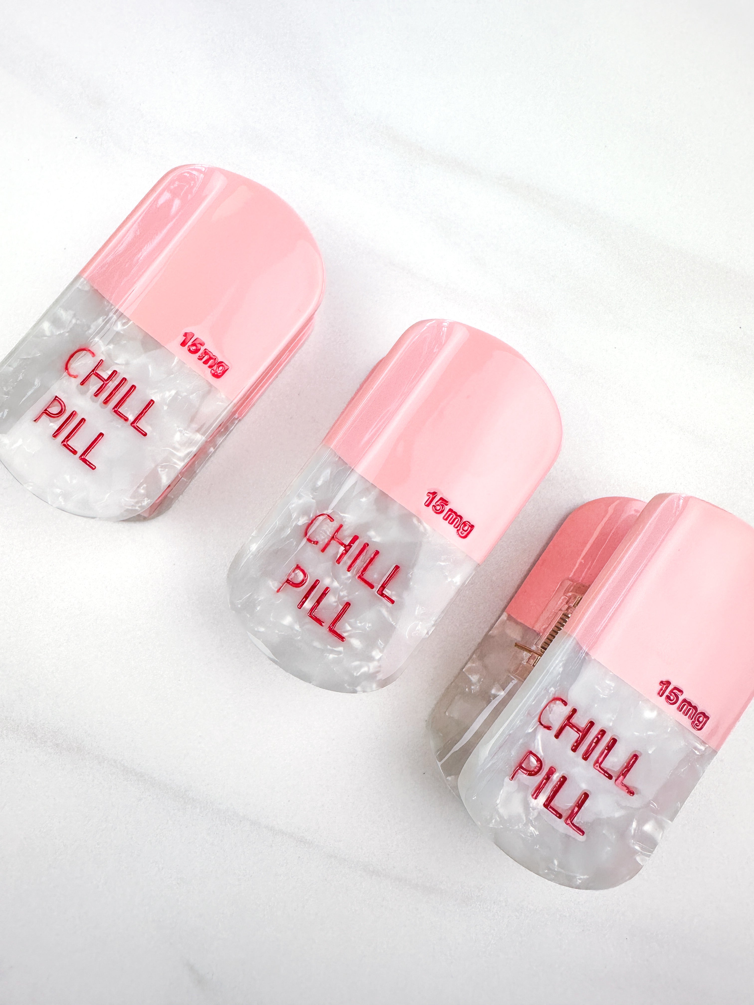 A group of hair claw clips that look like pink pills, featuring the Lilac Clip's glossy material and hinge closure for all hair types.
