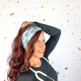 A woman confidently wears the Scrub In headband with a stethoscope, showcasing its versatile 3-in-1 twist style. Designed for function and style, perfect for workouts or workdays.