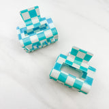 Checking In Lilac Clip: a 2-inch glossy turquoise checkered claw clip with a hinge closure, perfect for styling and keeping hair in place.