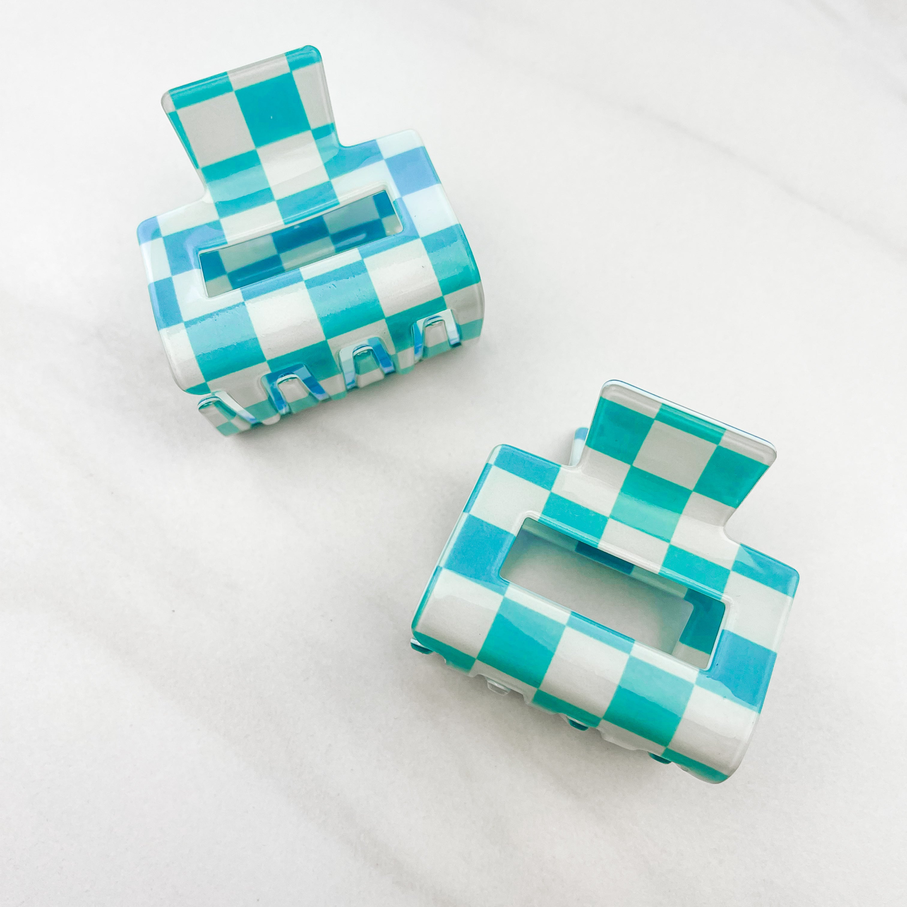 Checking In Lilac Clip: a 2-inch glossy turquoise checkered claw clip with a hinge closure, perfect for styling and keeping hair in place.