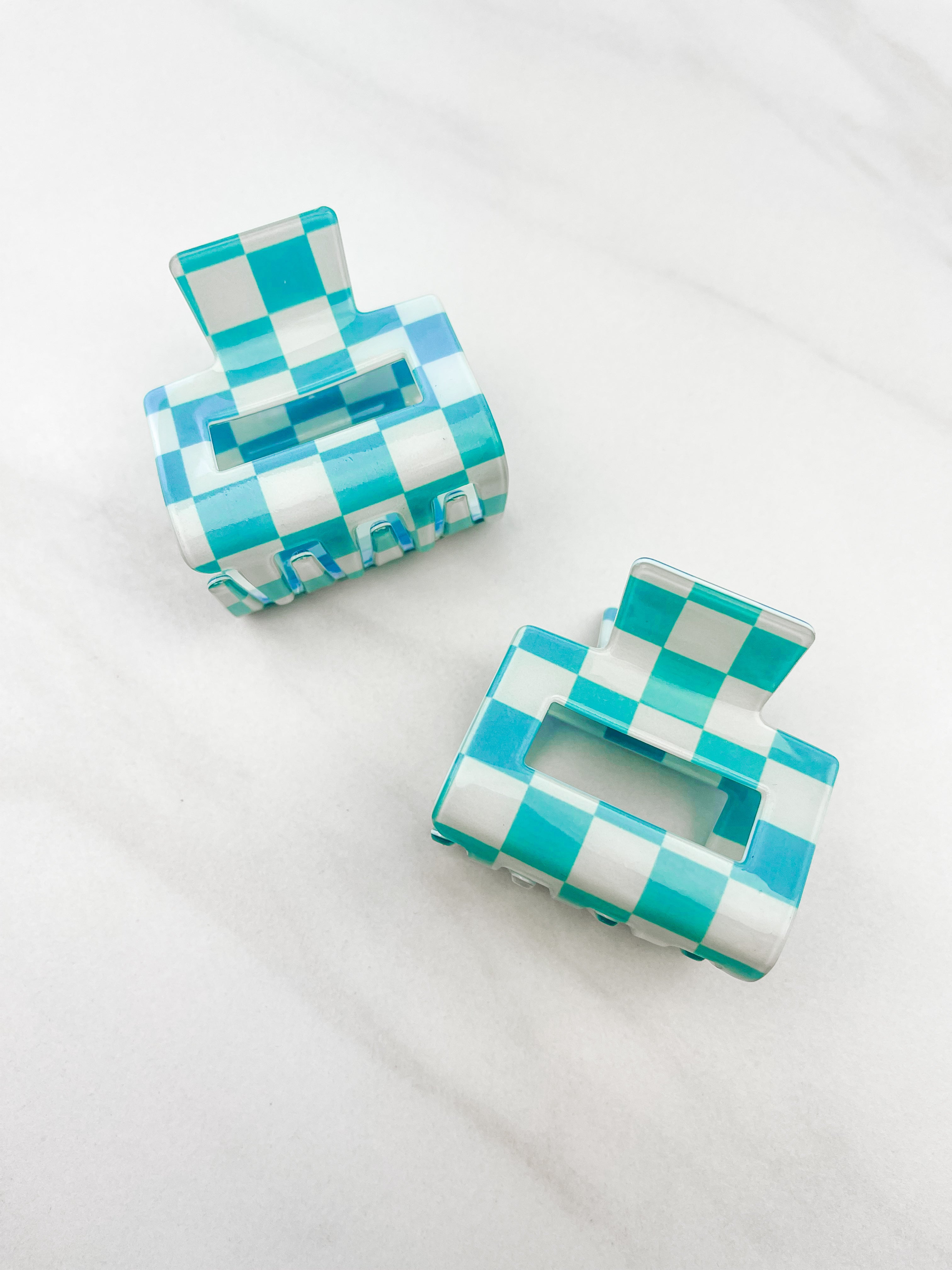 Checking In Lilac Clip: a 2-inch glossy turquoise checkered claw clip with a hinge closure, perfect for styling and keeping hair in place.