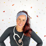 A woman confidently wears the Rainbows and Butterflies Headband, a functional twist-style accessory. Designed for comfort and versatility, machine washable with sweat-absorbent fabric. Perfect for workouts, shifts, or play.