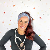A woman confidently wears the Rainbows and Butterflies Headband, a functional twist-style accessory. Designed for comfort and versatility, machine washable with sweat-absorbent fabric. Perfect for workouts, shifts, or play.