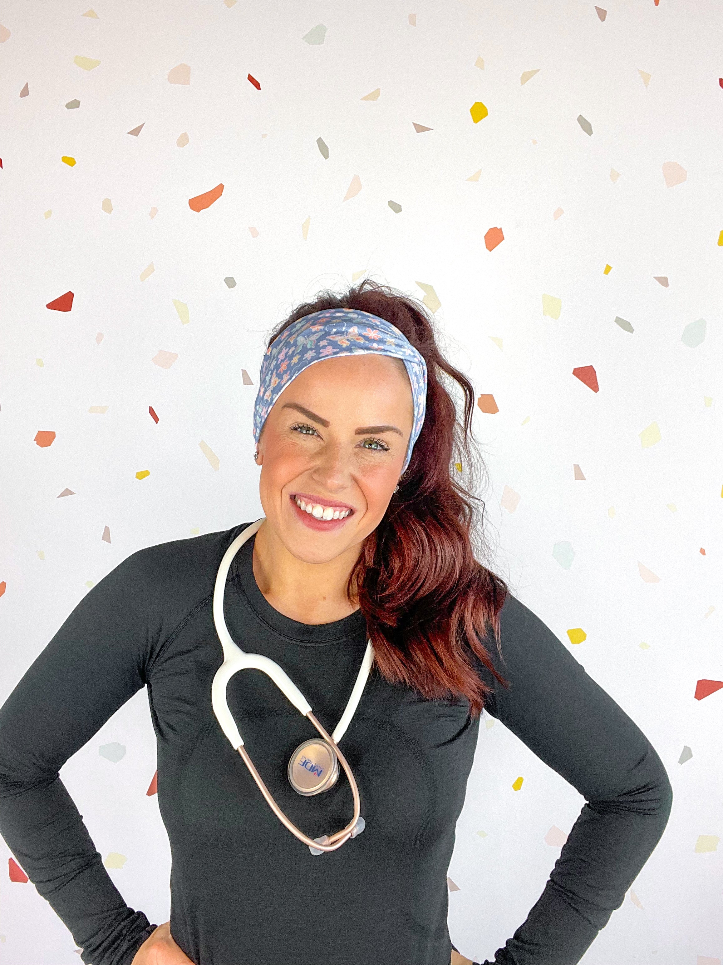 A woman confidently wears the Rainbows and Butterflies Headband, a functional twist-style accessory. Designed for comfort and versatility, machine washable with sweat-absorbent fabric. Perfect for workouts, shifts, or play.