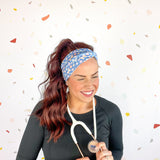 A woman confidently wears the Rainbows and Butterflies Headband, a functional twist-style accessory. Designed for comfort and versatility, machine washable with sweat-absorbent fabric. Perfect for workouts, shifts, or play.
