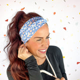A woman confidently wears the Rainbows and Butterflies Headband, a functional twist-style accessory. Designed for comfort and versatility, machine washable with sweat-absorbent fabric. Perfect for workouts, shifts, or play.