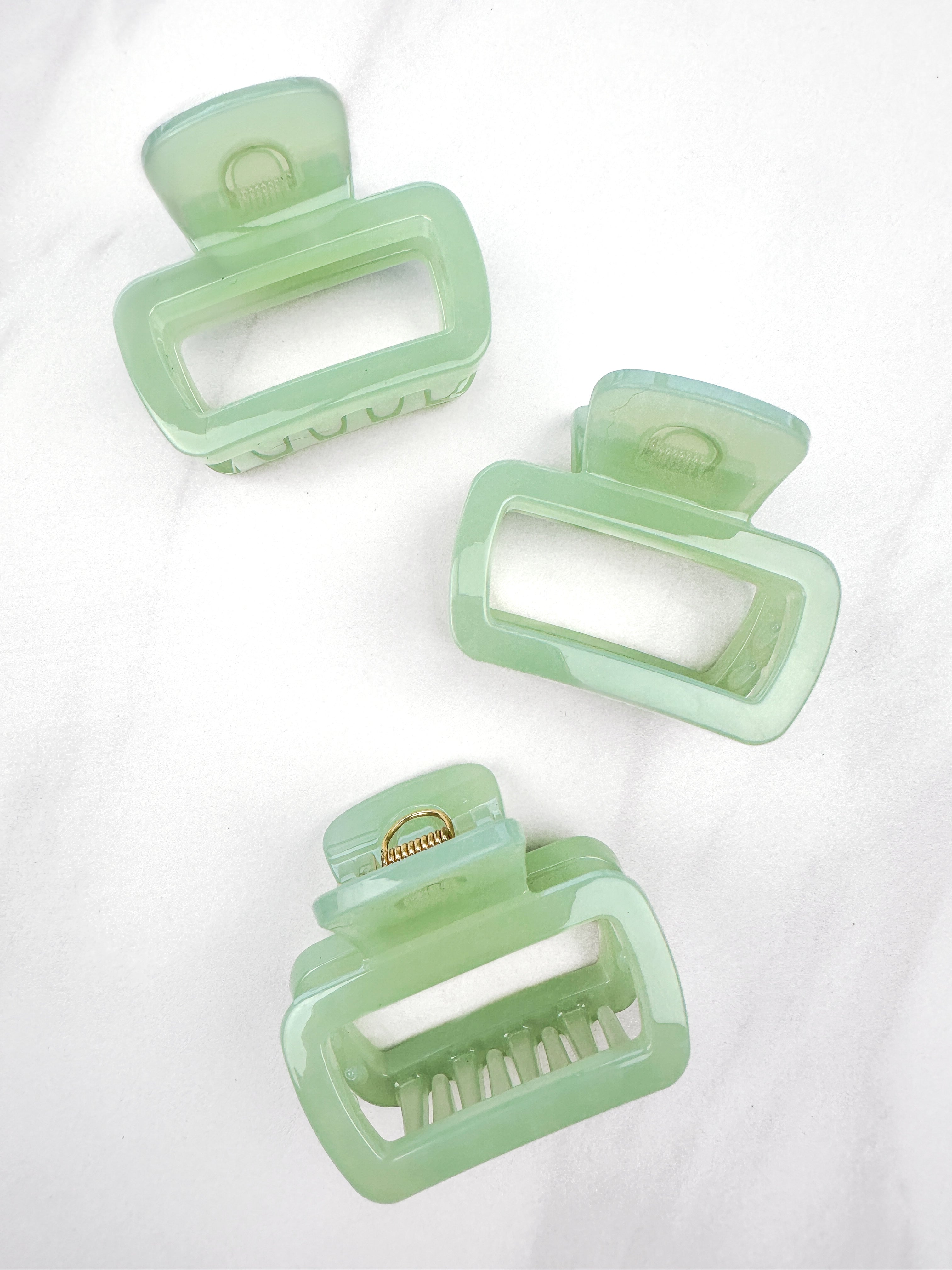 A close-up of a green Happy Hour Lilac Clip, a glossy hair accessory with a hinge closure, perfect for all hair types. 1.8 inches long.