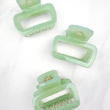 A close-up of a green Happy Hour Lilac Clip, a glossy hair accessory with a hinge closure, perfect for all hair types. 1.8 inches long.