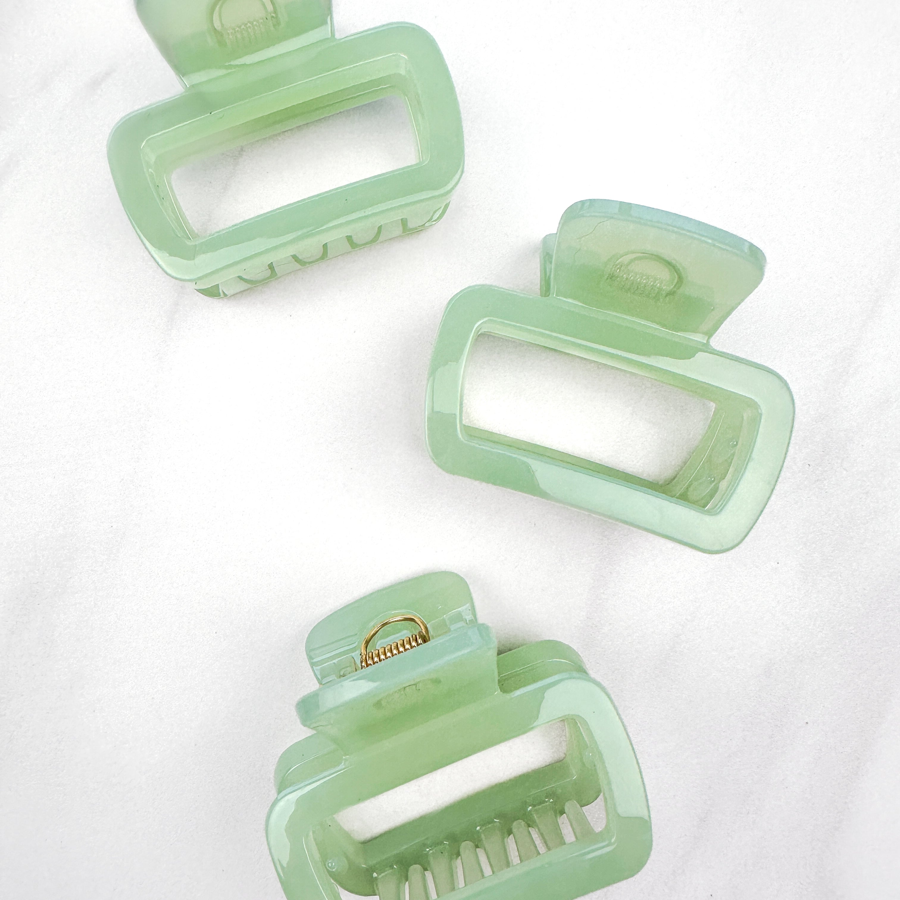 A close-up of a green Happy Hour Lilac Clip, a glossy hair accessory with a hinge closure, perfect for all hair types. 1.8 inches long.