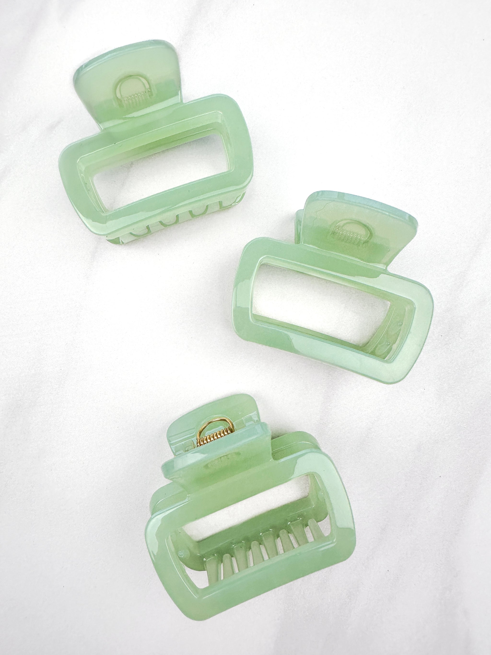 A close-up of a green Happy Hour Lilac Clip, a glossy hair accessory with a hinge closure, perfect for all hair types. 1.8 inches long.