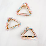 A group of pink, blue and white Endless Weekend Lilac Clips, triangle-shaped hair accessory, perfect for all hair types. Glossy finish, 1.9 inches long, hinge closure.