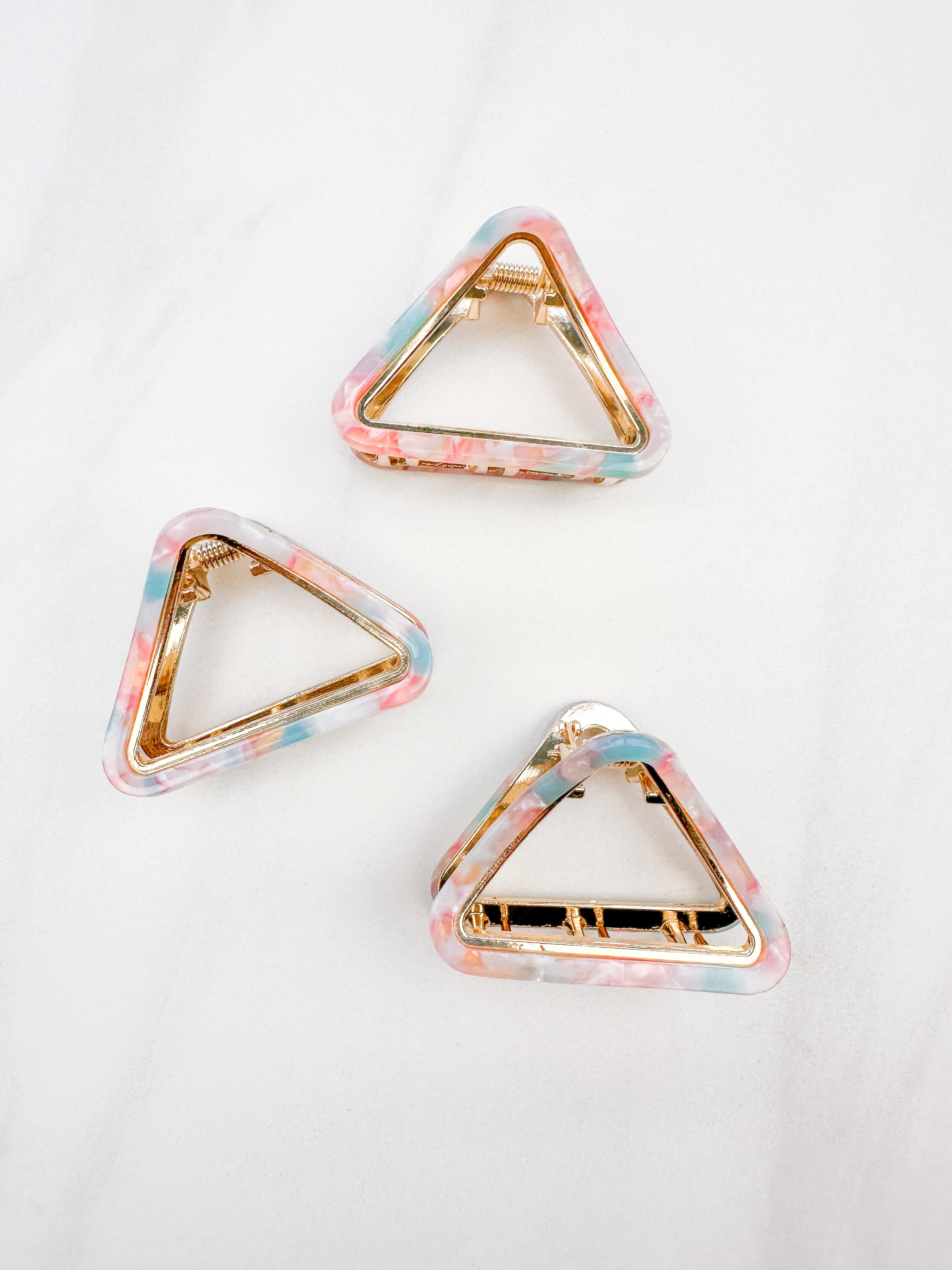 A group of pink, blue and white Endless Weekend Lilac Clips, triangle-shaped hair accessory, perfect for all hair types. Glossy finish, 1.9 inches long, hinge closure.