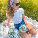 A woman confidently wears a Courtesy of Red, White and Blue headband outdoors, featuring a versatile 3-in-1 twist style for various looks. Designed for comfort and functionality, perfect for workouts or long shifts.