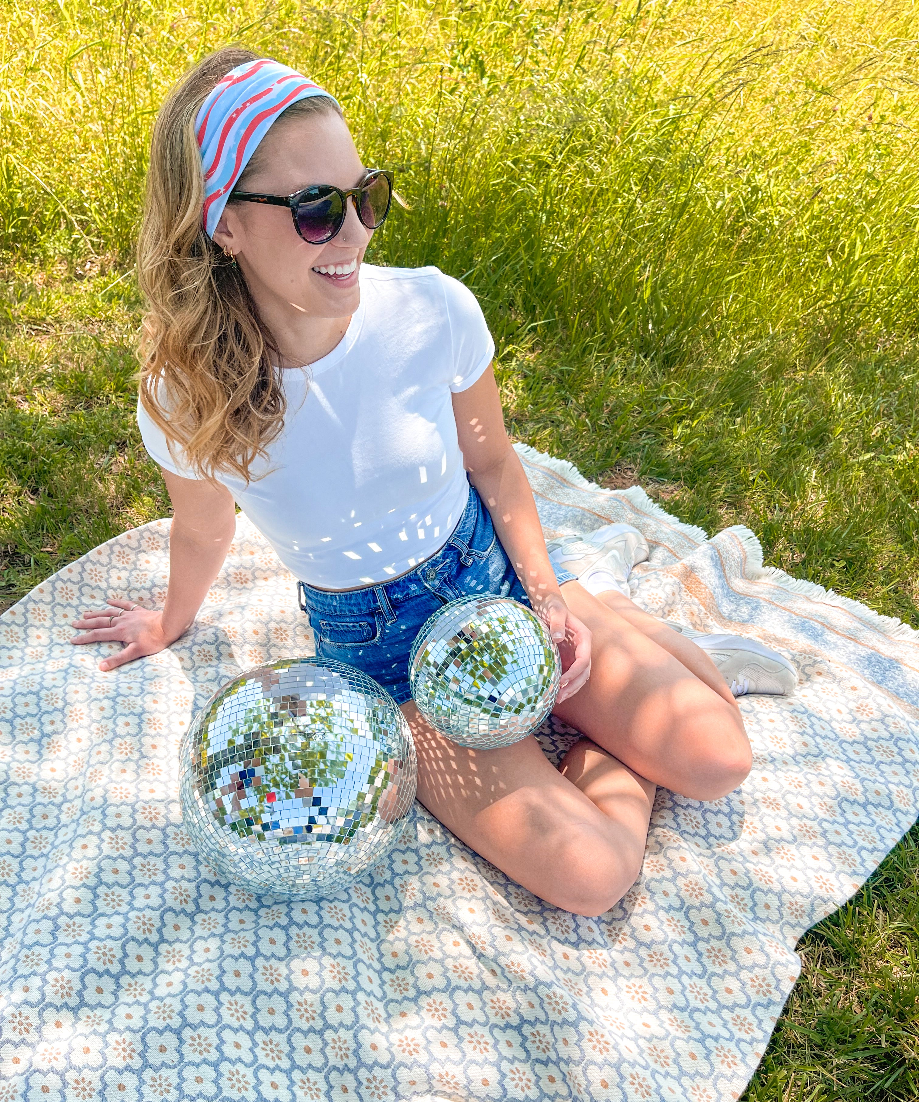A woman confidently wears a Courtesy of Red, White and Blue headband outdoors, featuring a versatile 3-in-1 twist style for various looks. Designed for comfort and functionality, perfect for workouts or long shifts.